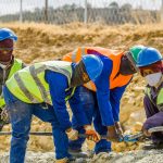 Team of construction workers in safety gear collaborating on a project outdoors in South Africa.